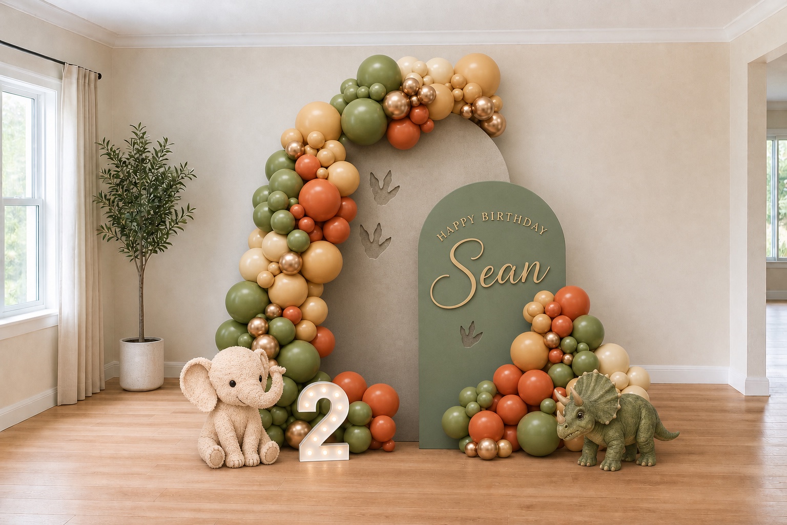 The same dining room with a sage, terracotta, and cream zoo-themed balloon installation, layered backdrops, a plush elephant, an illuminated number two, a triceratops, and gold birthday lettering for Sean